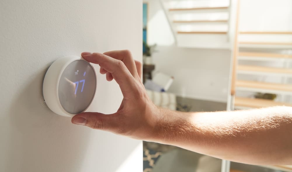 Close Up Of Male Hand Adjusting Digital Central Heating Thermostat In Home to save energy